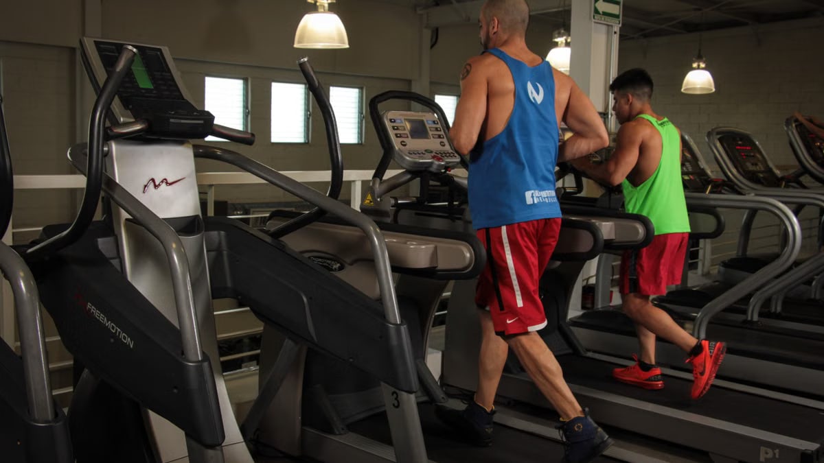 Two men running on treadmills in a modern gym, promoting fitness and health.